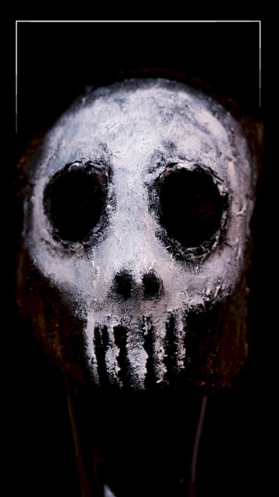 Close-up art of a white painted skull mask with rough texture and hollow black eyes against a black background.
