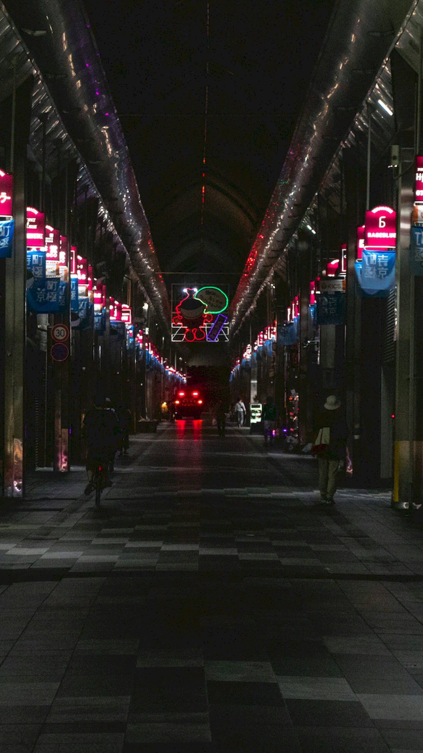 Dark vertical view of a Japanese covered shopping street at night with neon signs and people walking, 4K phone wallpaper.