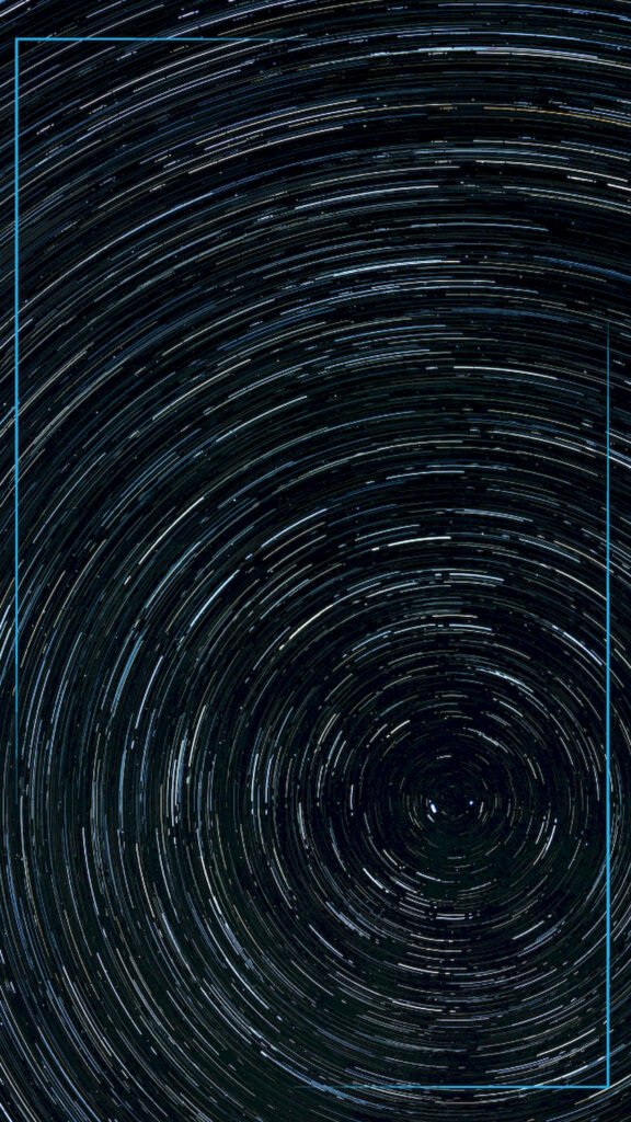 Long exposure photography of the night sky showing stars forming concentric circular trails around a central point in a deep blue sky.