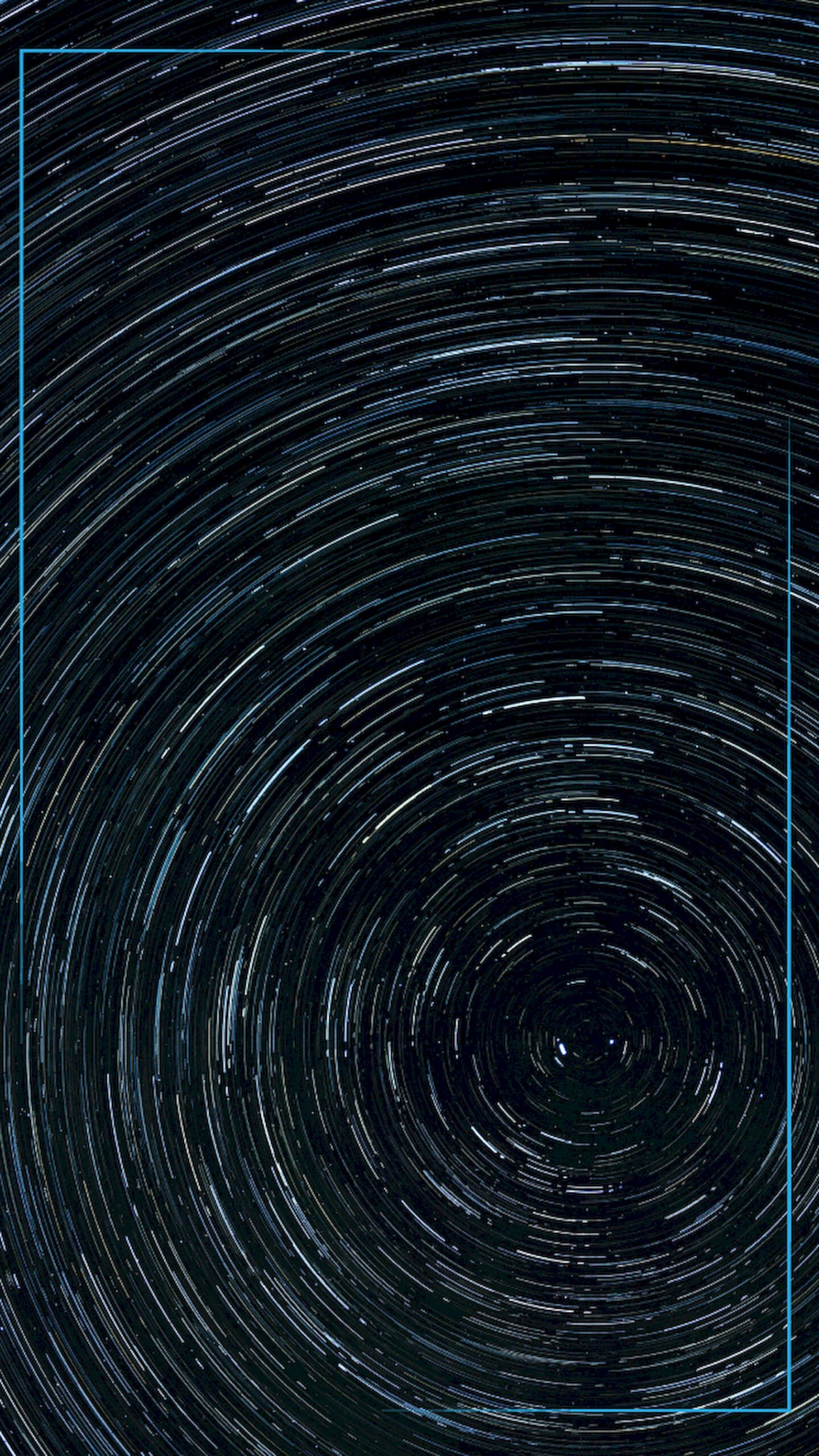 Long exposure photography of the night sky showing stars forming concentric circular trails around a central point in a deep blue sky.